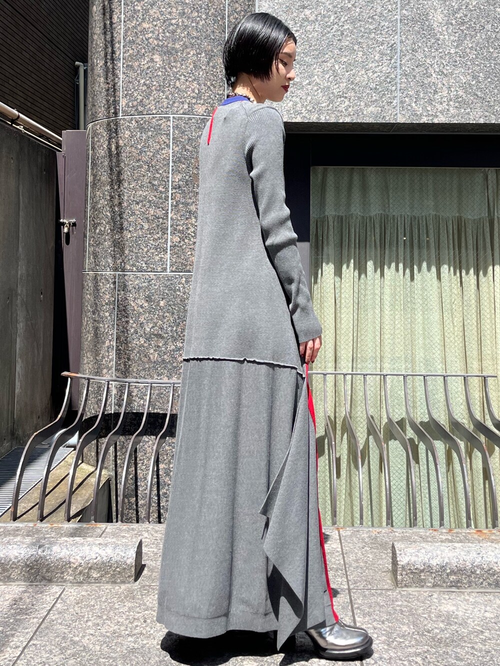 グレー系のワンピース、シルバー系のブーツ、シルバー系のネックレスを着用したレディースの秋コーディネートの3枚目の写真