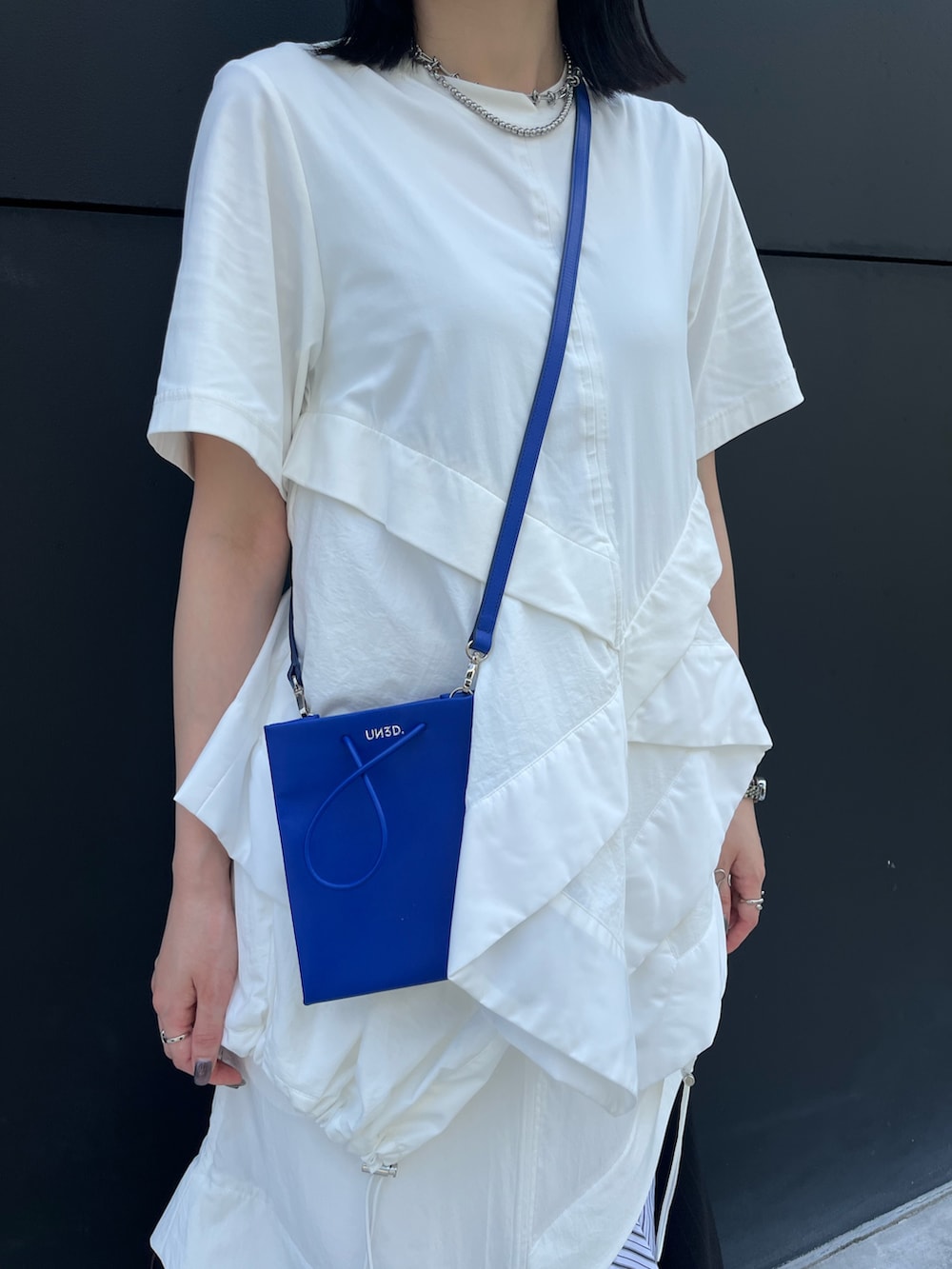 その他のスカート、ブルー系のショルダーバッグ、ブラック系のスニーカーを着用したレディースの夏コーディネートの7枚目の写真