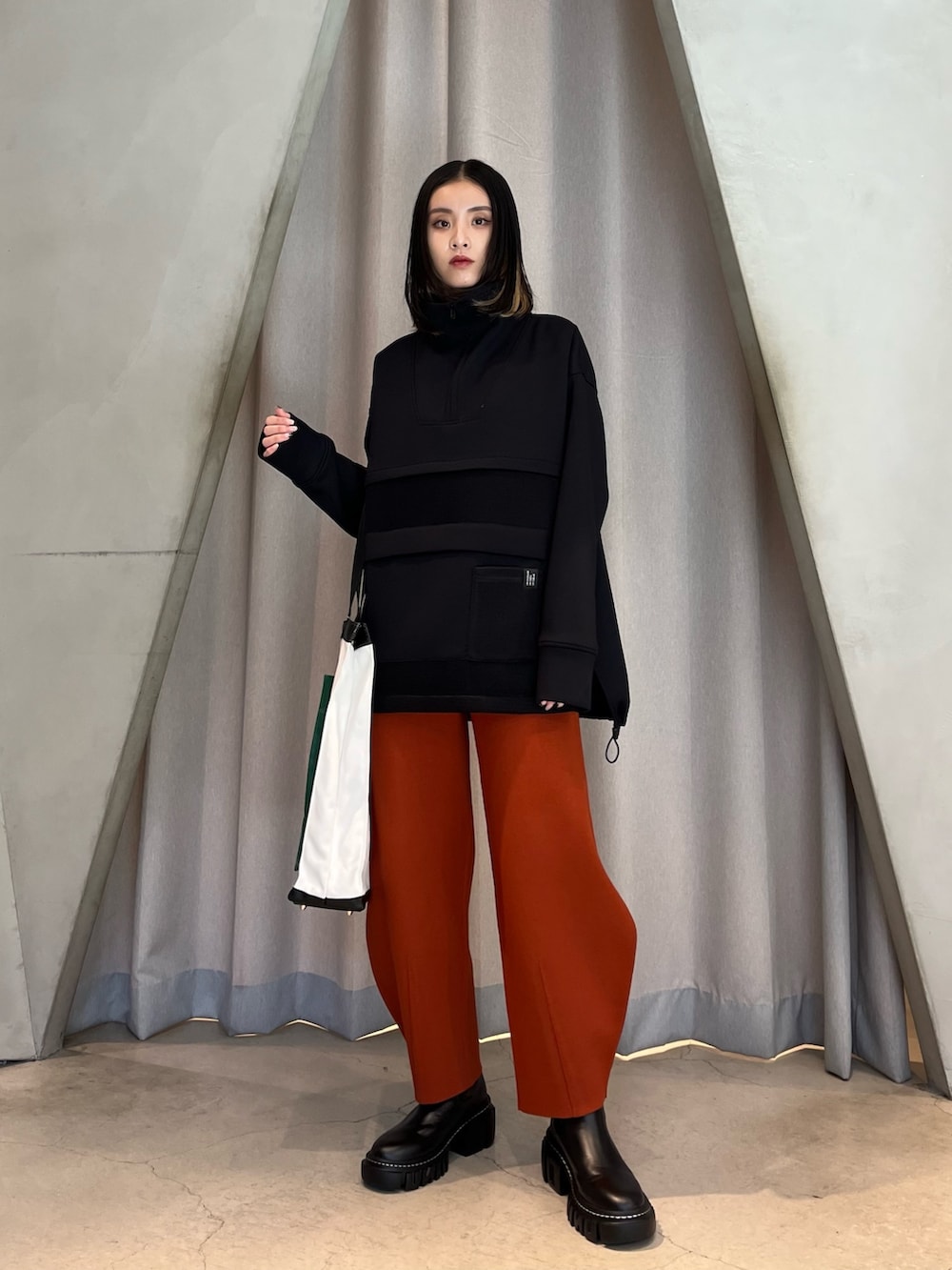 ブラック系のスウェット、オレンジ系のその他パンツ、ブラック系のブーツを着用したレディースの秋コーディネートの2枚目の写真