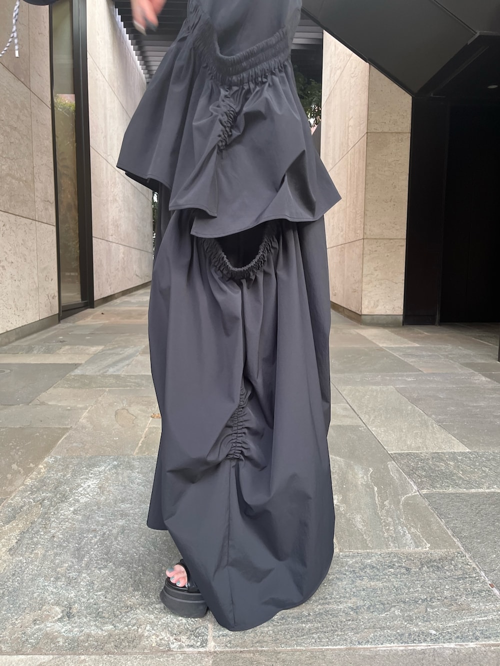 ブラック系のタンクトップ、ブラック系のスカート、ブラック系のサンダルを着用したレディースの春コーディネートの10枚目の写真