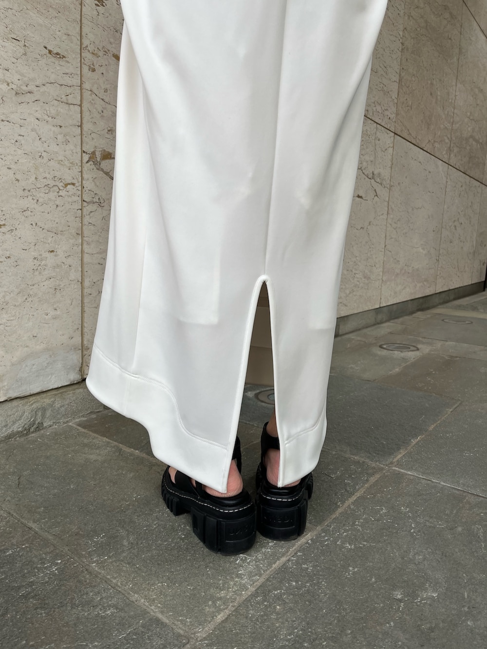 ホワイト系のワンピース、ブラック系のサンダル、ブラック系のイヤリングを着用したレディースの冬コーディネートの7枚目の写真