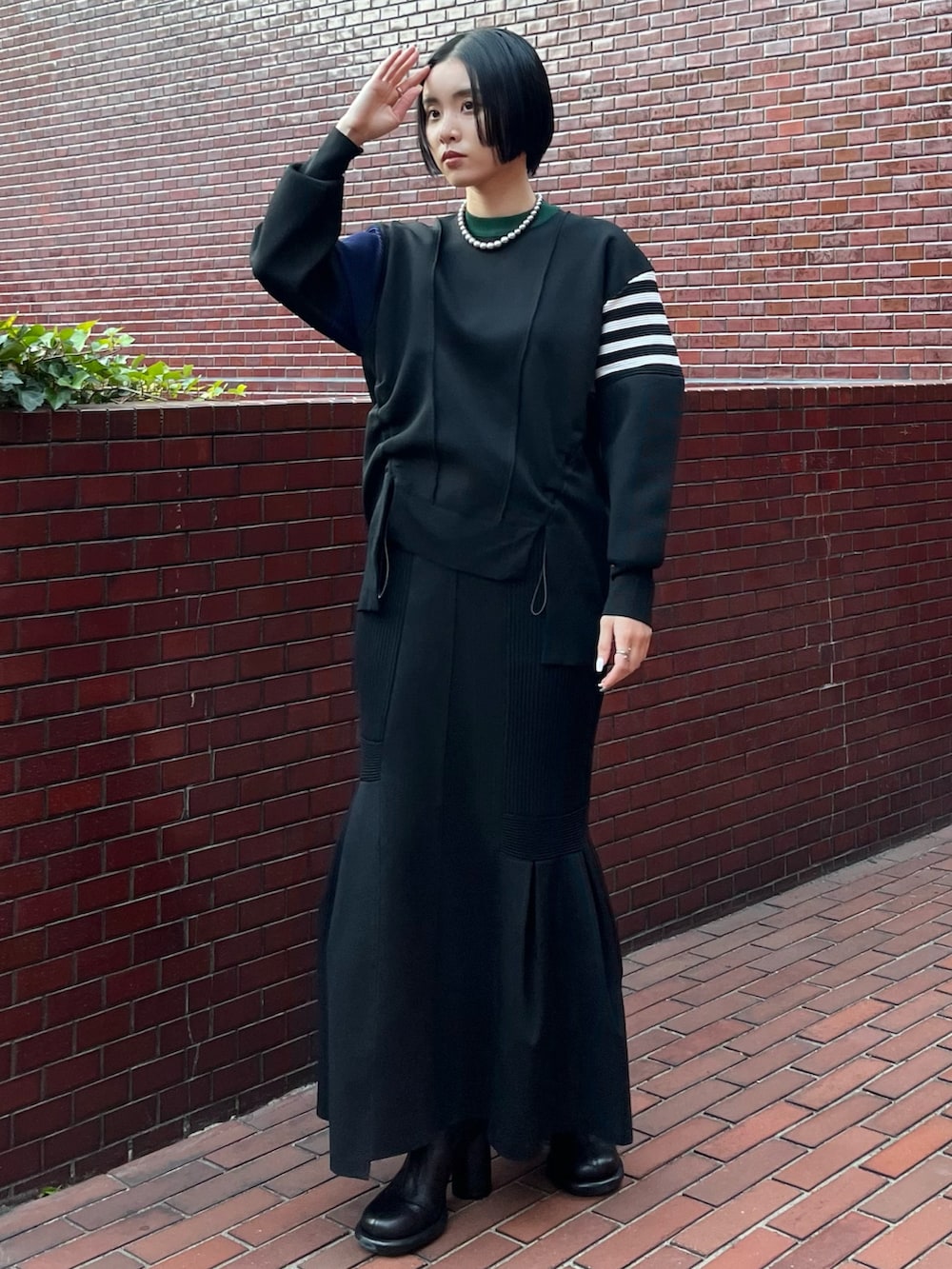 ブラック系のニット/セーター、ブラック系のスカート、ブラック系のブーツを着用したレディースの冬コーディネートの2枚目の写真