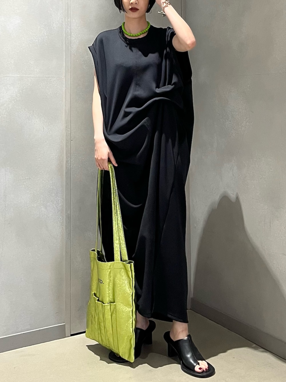 ブラック系のワンピース、ブラック系のサンダル、イエロー系のトートバッグを着用したレディースの夏コーディネートの2枚目の写真