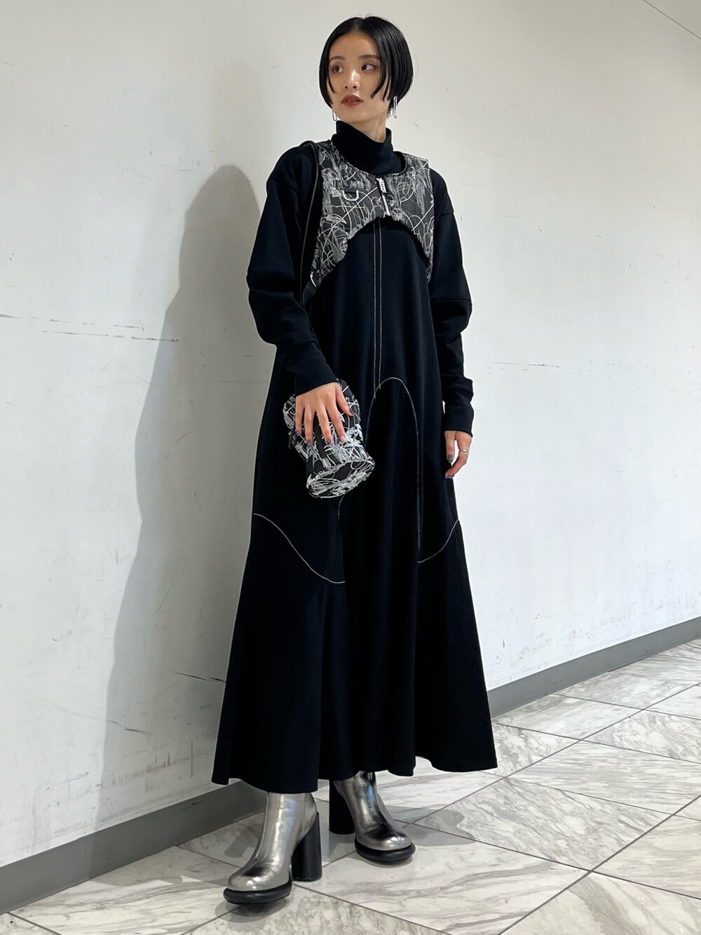 ブラック系のワンピース、ブラック系のベスト、シルバー系のブーツを着用したレディースの秋コーディネートの2枚目の写真