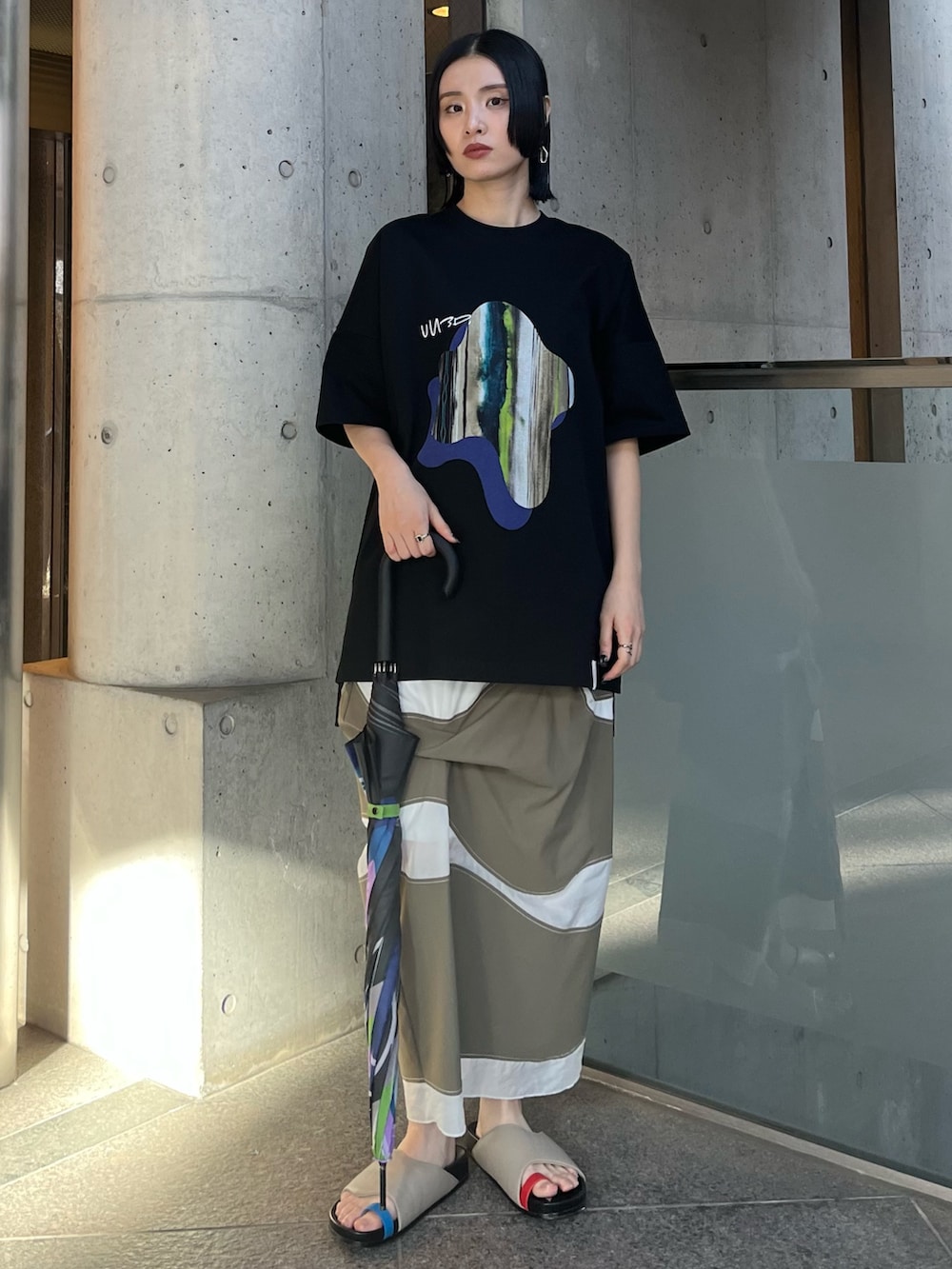 ブラック系のTシャツ/カットソー、ブラック系の長傘、ブラック系のイヤリングを着用したレディースの春コーディネートの2枚目の写真