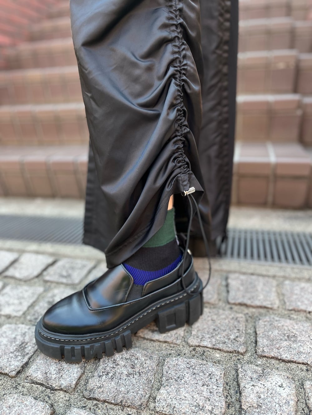 ブラック系のワンピース、ブラック系のローファー、シルバー系のイヤリングを着用したレディースの秋コーディネートの7枚目の写真