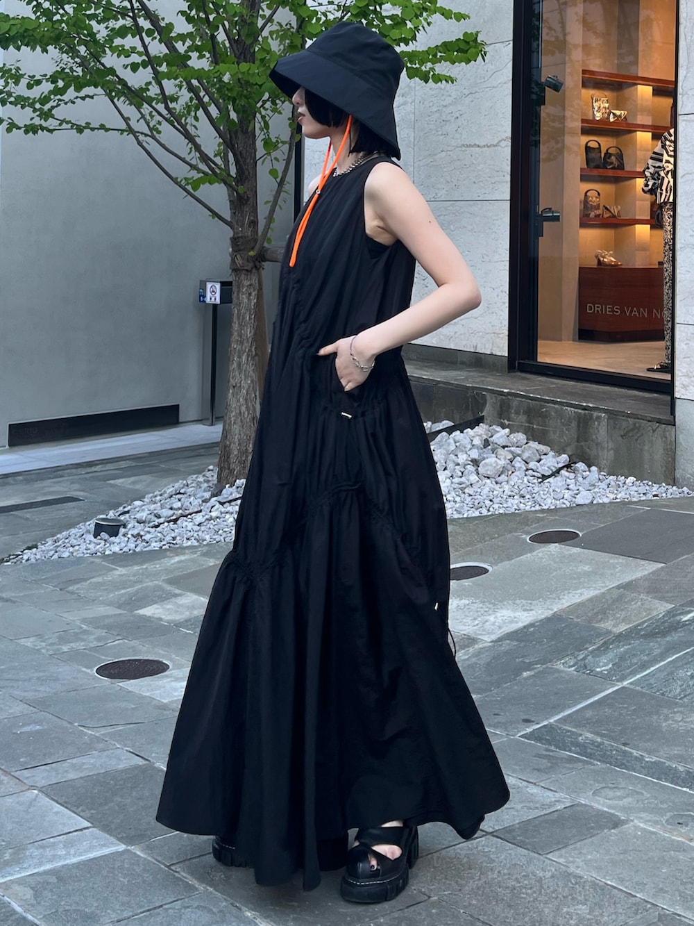 ブラック系のワンピース、ブラック系のサンダル、ブラック系のハットを着用したレディースの春コーディネートの2枚目の写真