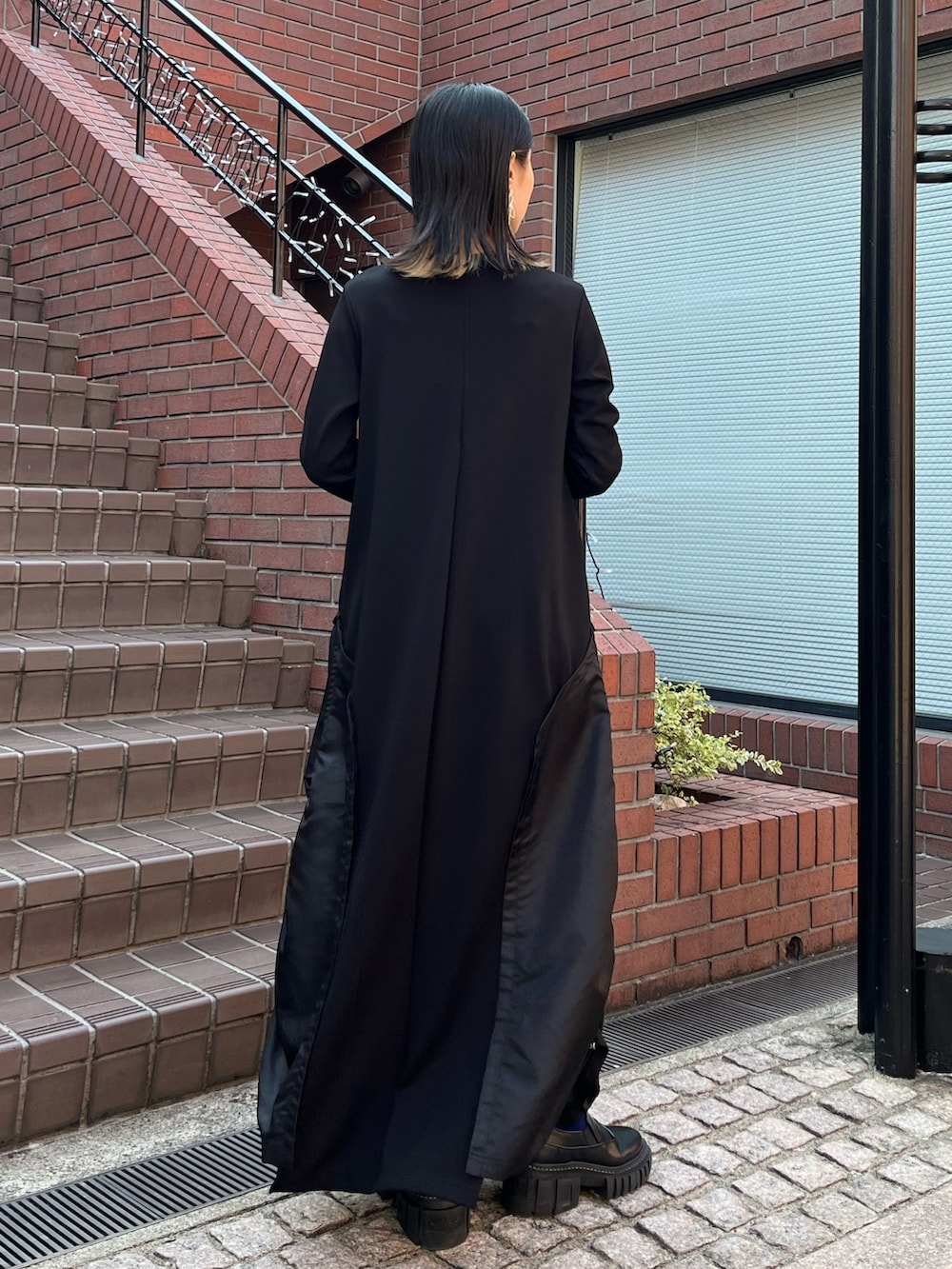 ブラック系のワンピース、ブラック系のローファー、シルバー系のイヤリングを着用したレディースの秋コーディネートの4枚目の写真