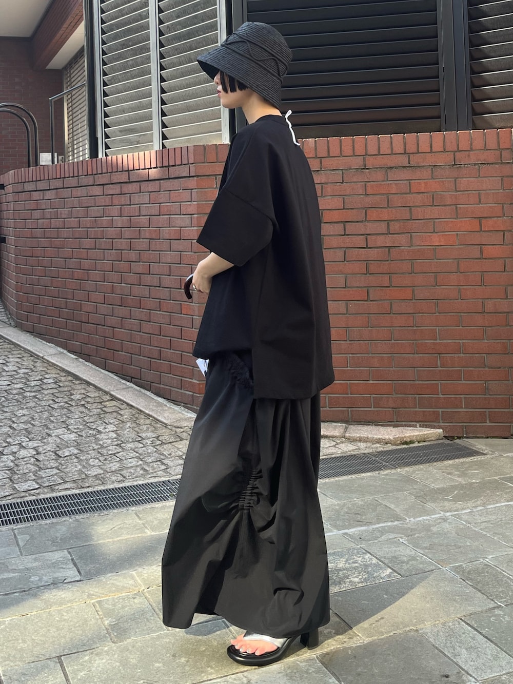 ブラック系のTシャツ/カットソー、ブラック系のその他パンツ、シルバー系のサンダルを着用したレディースの春コーディネートの2枚目の写真