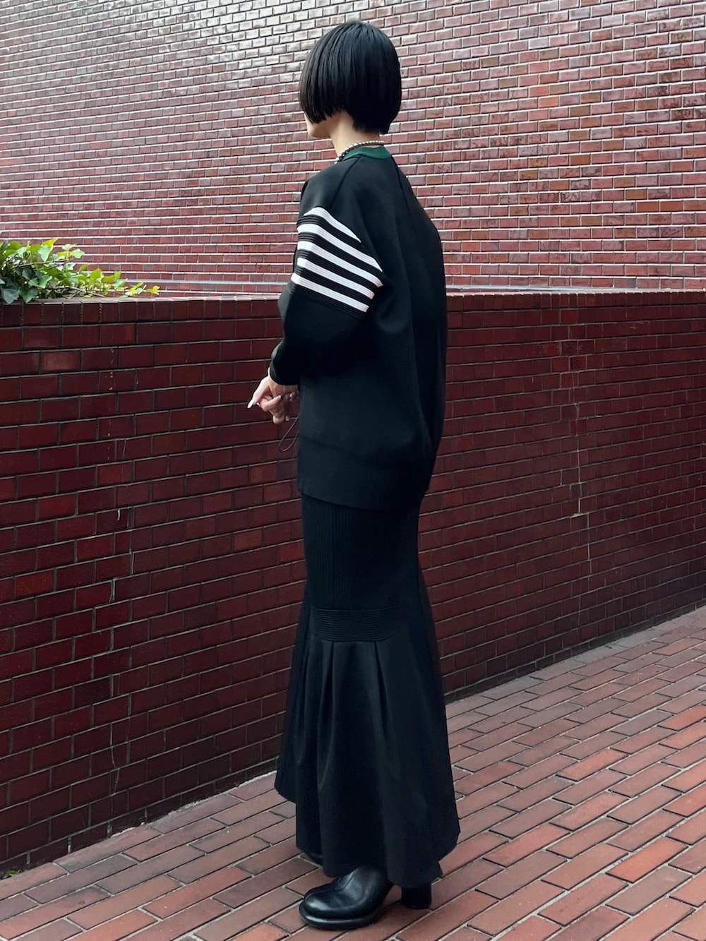 ブラック系のニット/セーター、ブラック系のスカート、ブラック系のブーツを着用したレディースの冬コーディネートの3枚目の写真