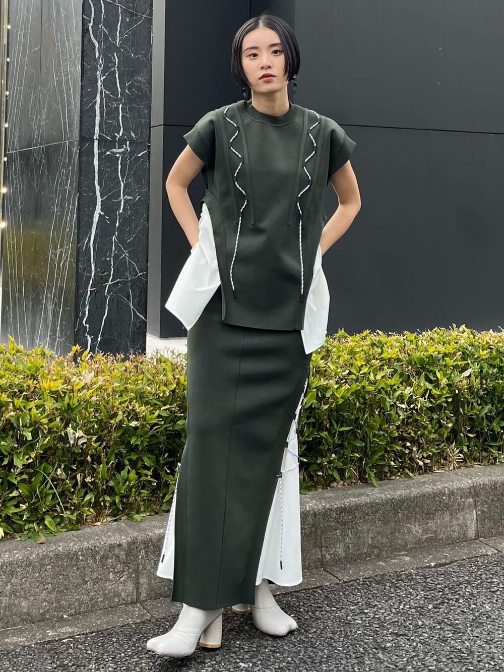 グリーン系のニット/セーター、グリーン系のスカート、ベージュ系のブーツを着用したレディースの春コーディネートの2枚目の写真