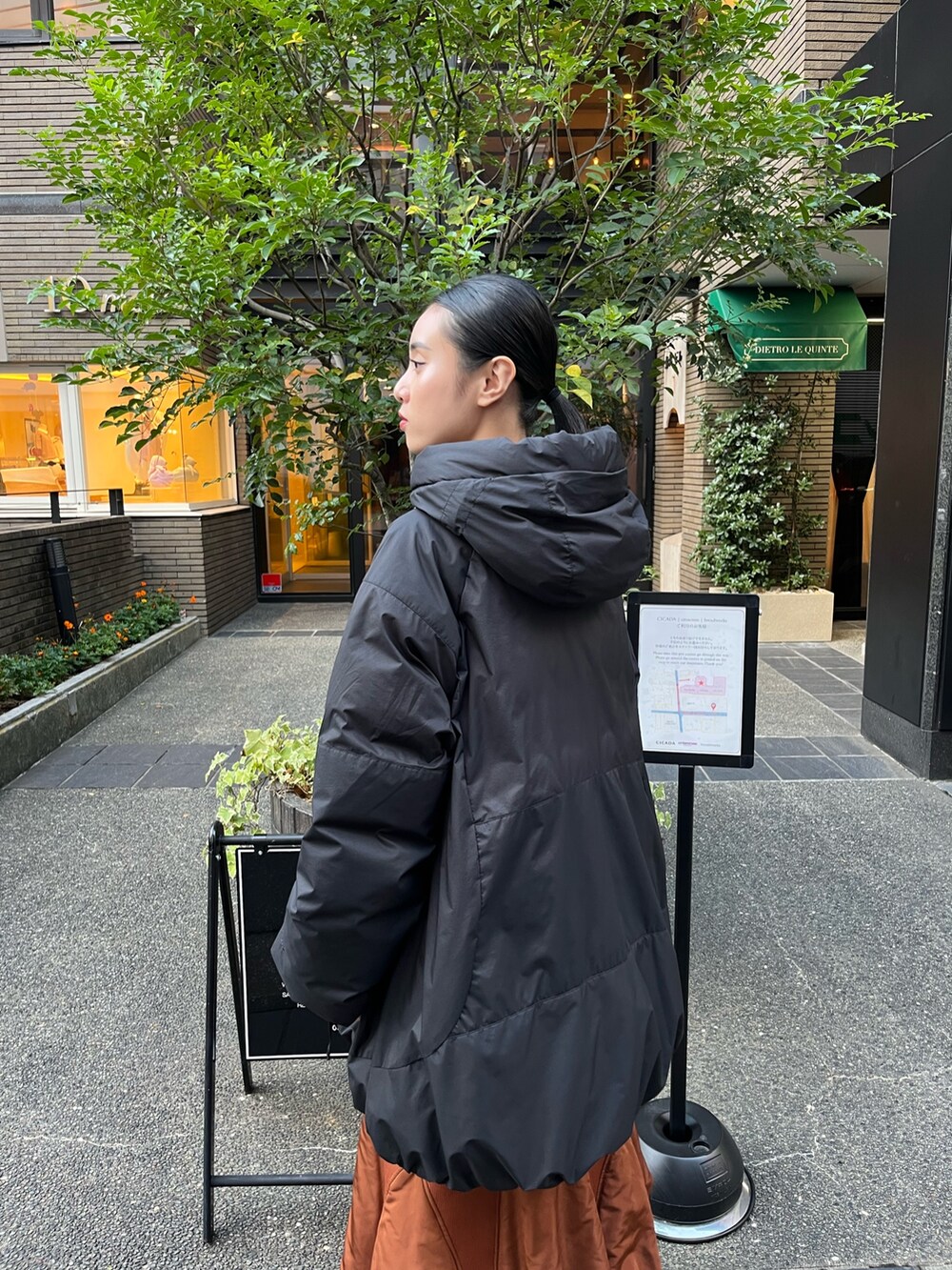 ブラック系のダウンジャケット/コート、イエロー系のスカート、ベージュ系のブーツを着用したレディースの秋コーディネートの6枚目の写真