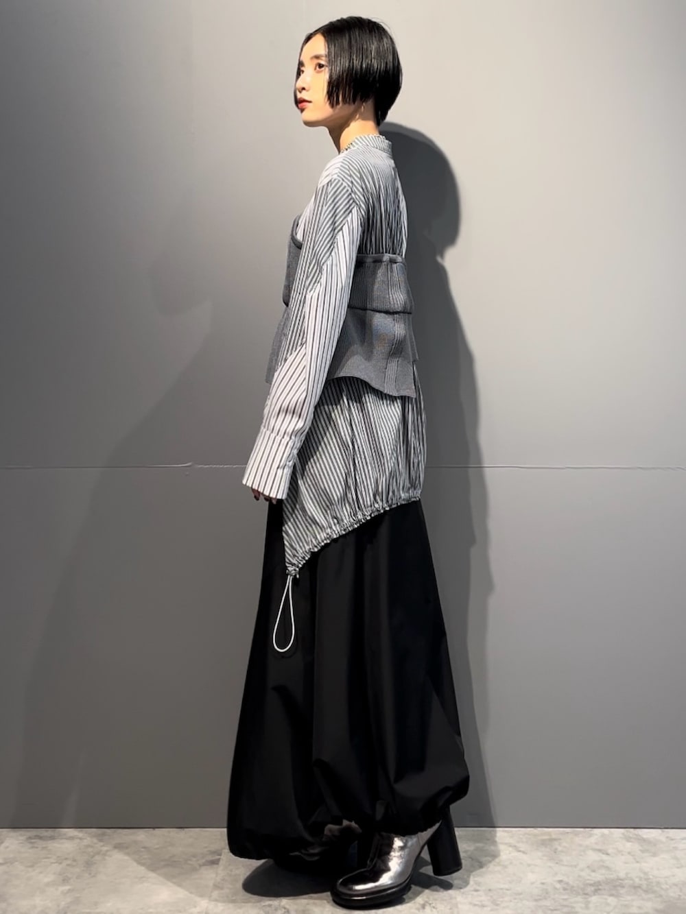 グレー系のシャツ/ブラウス、ブラック系のスカート、シルバー系のブーツを着用したレディースの秋コーディネートの3枚目の写真