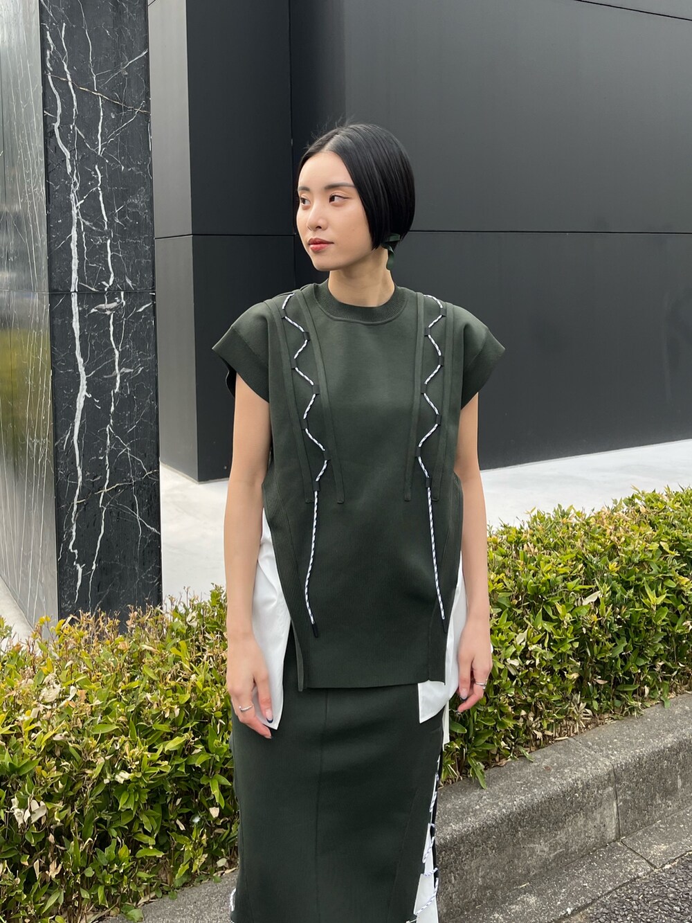 グリーン系のニット/セーター、グリーン系のスカート、ベージュ系のブーツを着用したレディースの春コーディネートの5枚目の写真