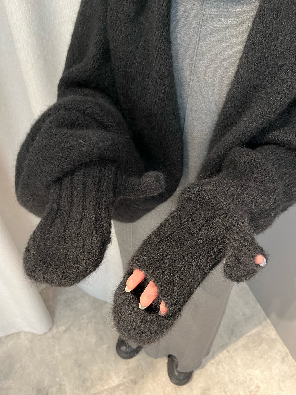 グレー系のワンピース、ブラック系のブーツ、ブラック系のマフラーを着用したレディースの秋コーディネートの6枚目の写真