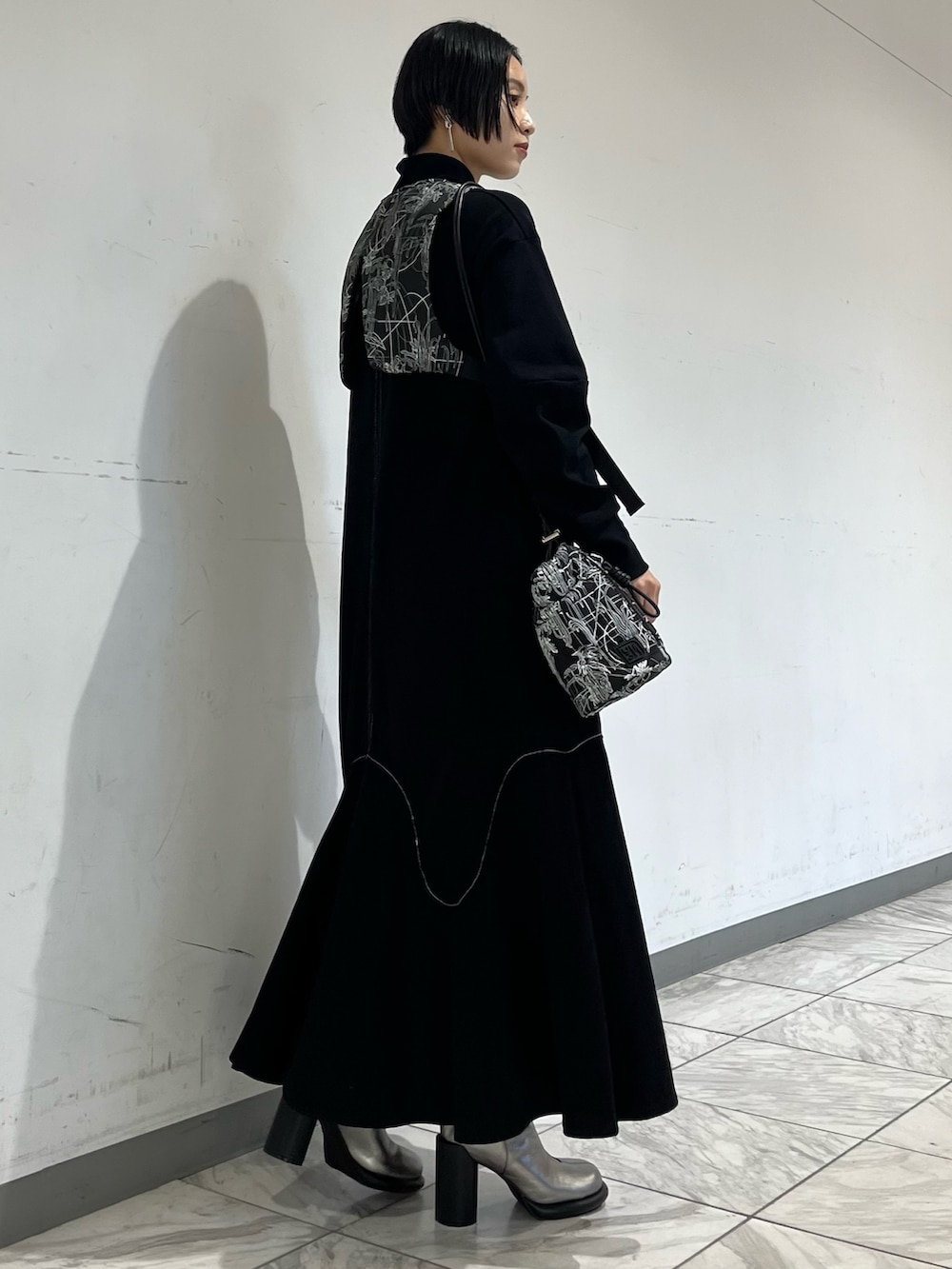 ブラック系のワンピース、ブラック系のベスト、シルバー系のブーツを着用したレディースの秋コーディネートの4枚目の写真