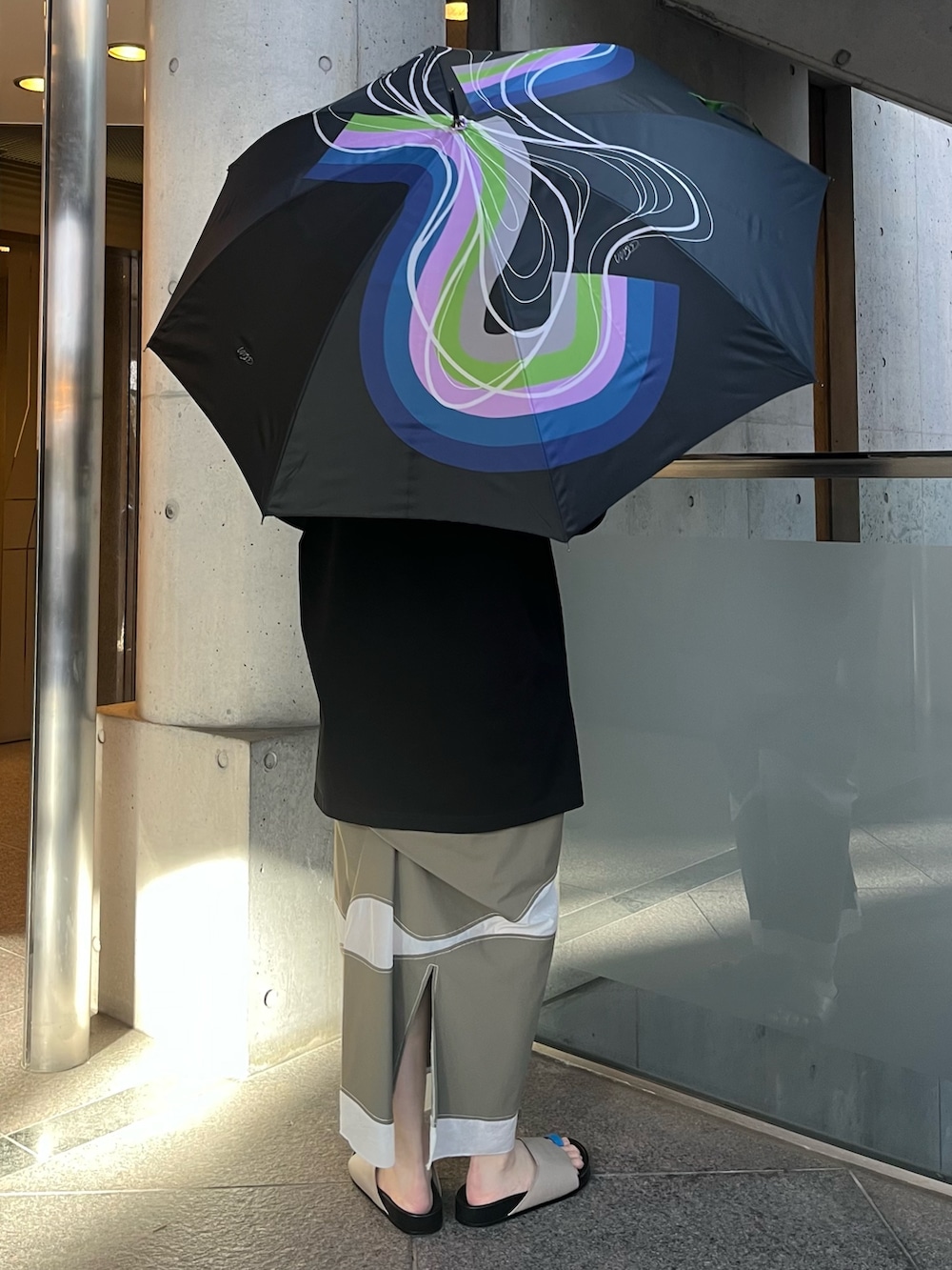 ブラック系のTシャツ/カットソー、ブラック系の長傘、ブラック系のイヤリングを着用したレディースの春コーディネートの3枚目の写真