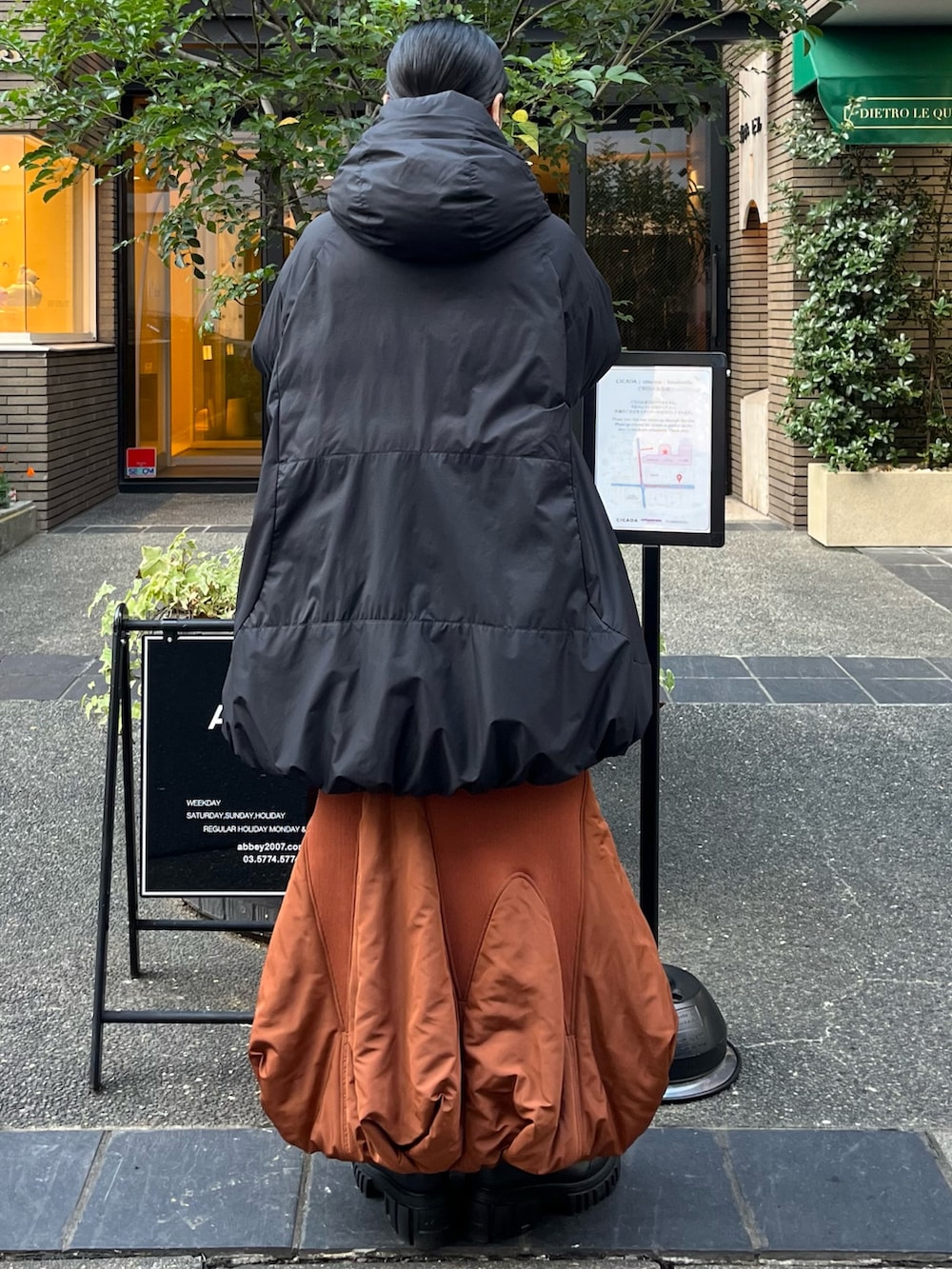 ブラック系のダウンジャケット/コート、イエロー系のスカート、ベージュ系のブーツを着用したレディースの秋コーディネートの2枚目の写真