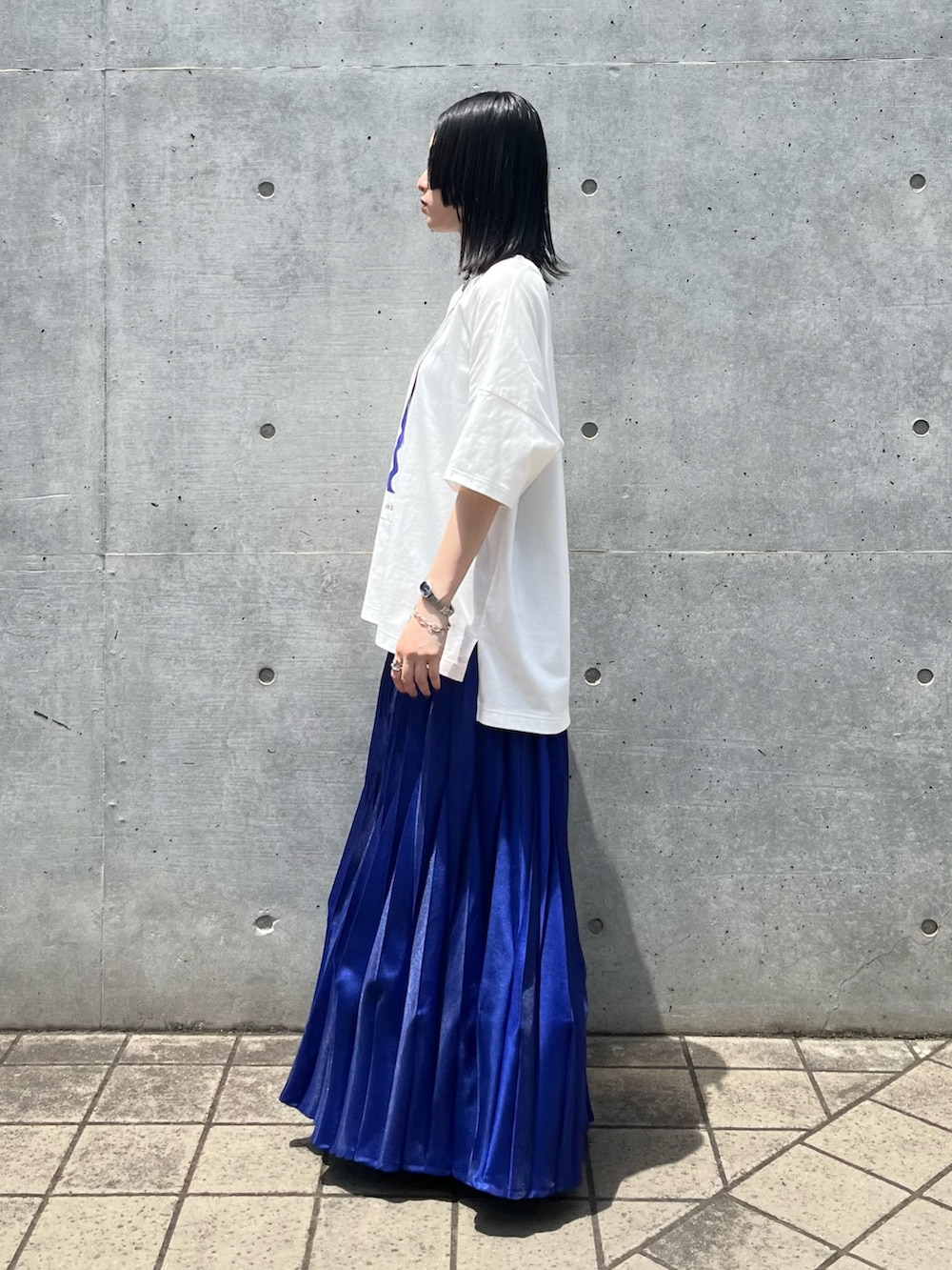 ホワイト系のTシャツ/カットソー、ブルー系のスカート、ブラック系のスニーカーを着用したレディースの夏コーディネートの3枚目の写真