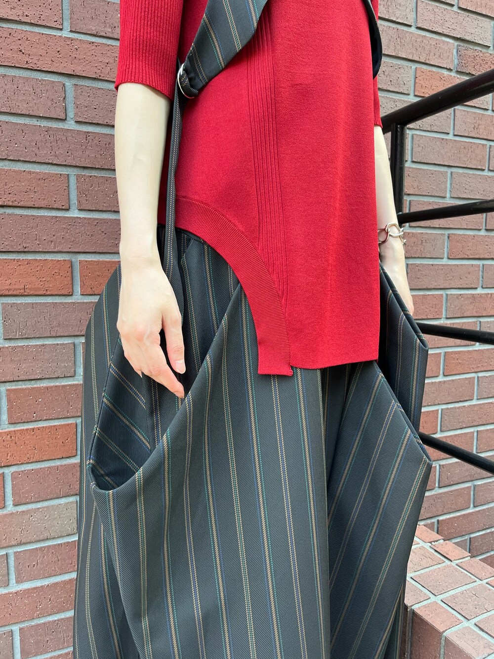 レッド系のニット/セーター、ブラック系のベスト、ブラック系のスカートを着用したレディースの夏コーディネートの9枚目の写真