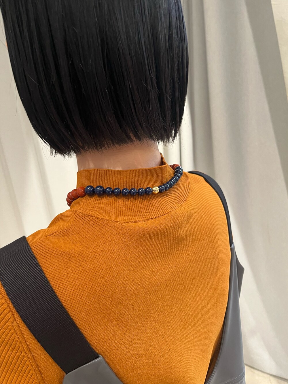 イエロー系のニット/セーター、グレー系のその他トップス、グレー系のスカートを着用したレディースの秋コーディネートの8枚目の写真