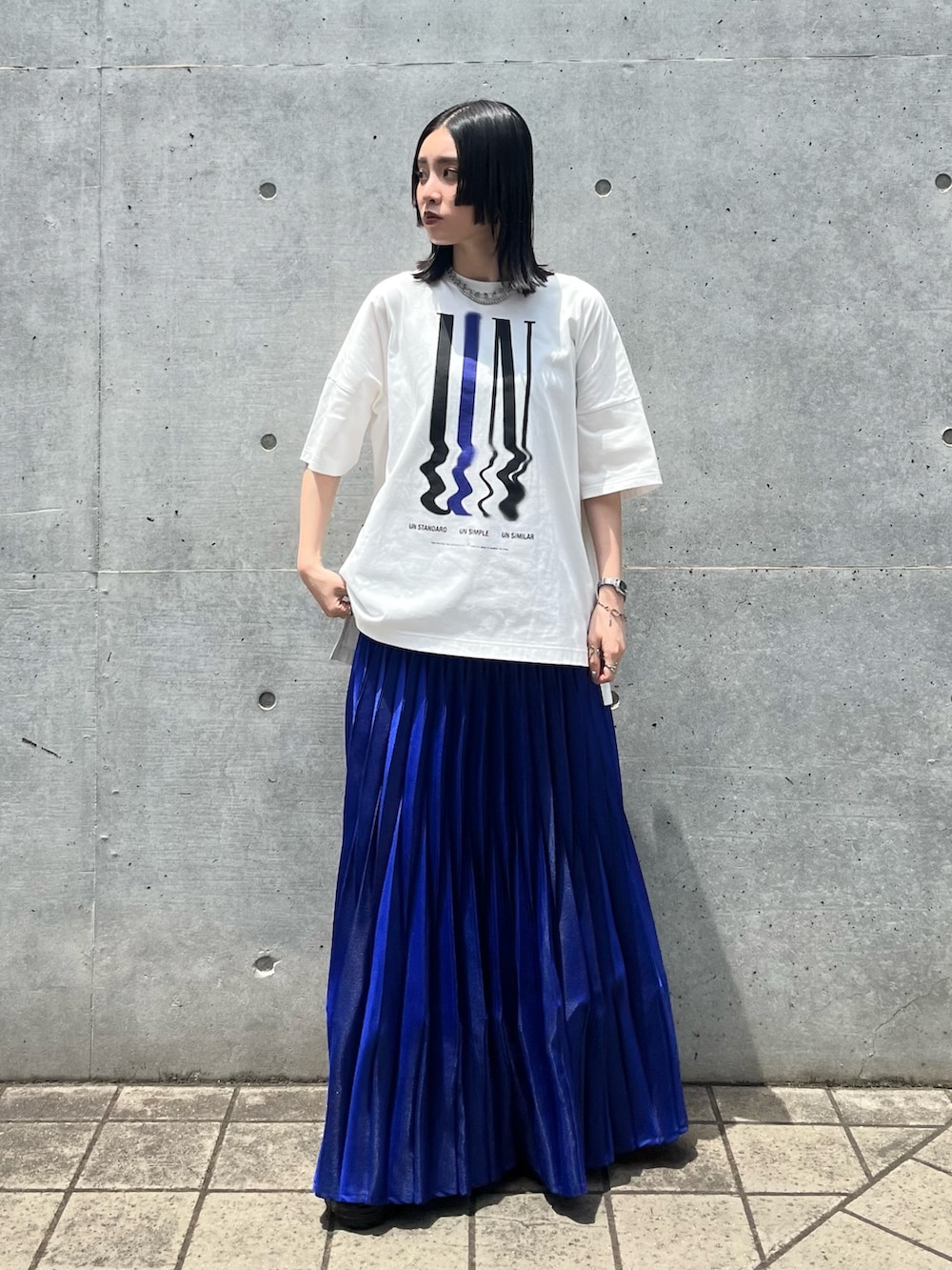 ホワイト系のTシャツ/カットソー、ブルー系のスカート、ブラック系のスニーカーを着用したレディースの夏コーディネートの2枚目の写真
