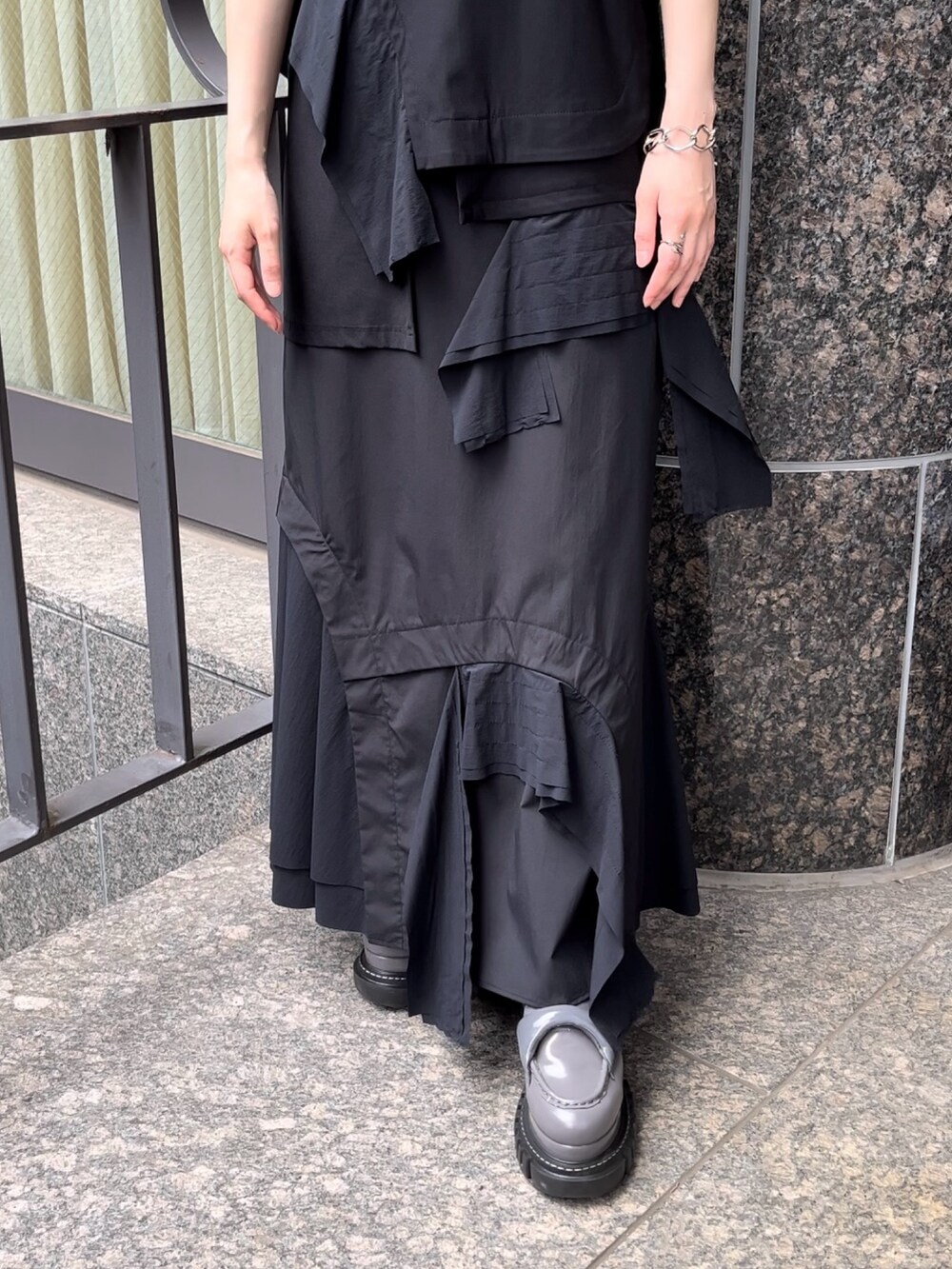 ブラック系のTシャツ/カットソー、ブラック系のスカート、グレー系のローファーを着用したレディースの秋コーディネートの6枚目の写真