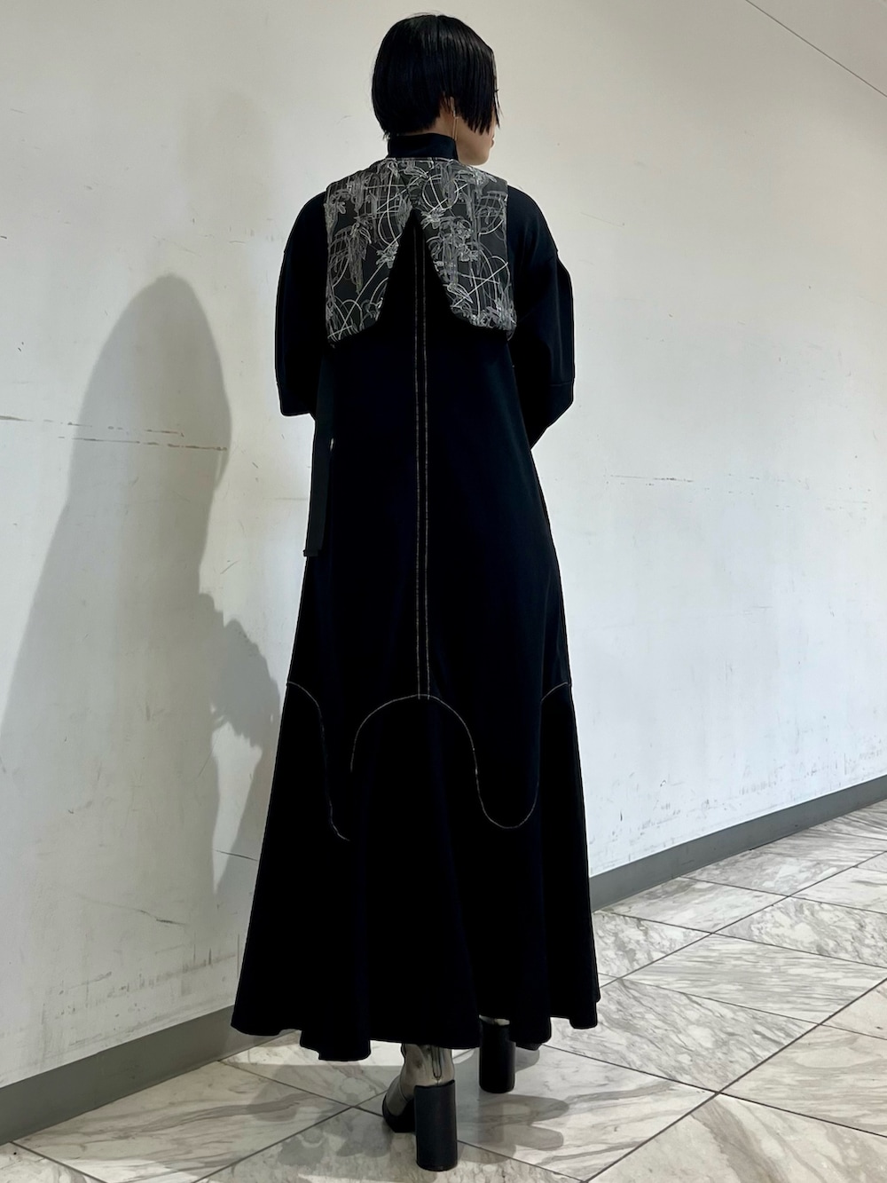 ブラック系のワンピース、ブラック系のベスト、シルバー系のブーツを着用したレディースの秋コーディネートの5枚目の写真