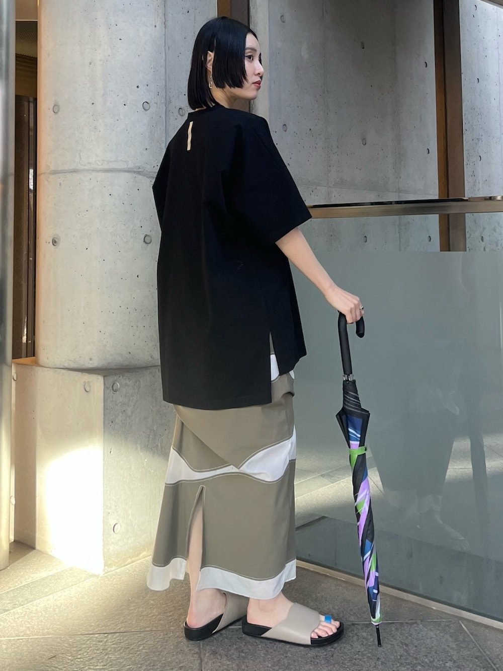 ブラック系のTシャツ/カットソー、ブラック系の長傘、ブラック系のイヤリングを着用したレディースの春コーディネートの4枚目の写真