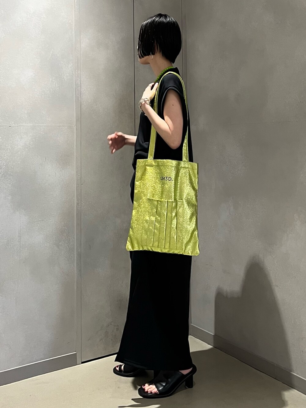 ブラック系のワンピース、ブラック系のサンダル、イエロー系のトートバッグを着用したレディースの夏コーディネートの4枚目の写真