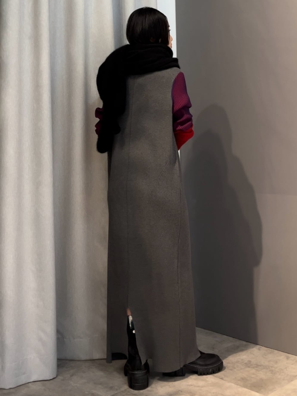 グレー系のワンピース、ブラック系のブーツ、ブラック系のマフラーを着用したレディースの秋コーディネートの3枚目の写真