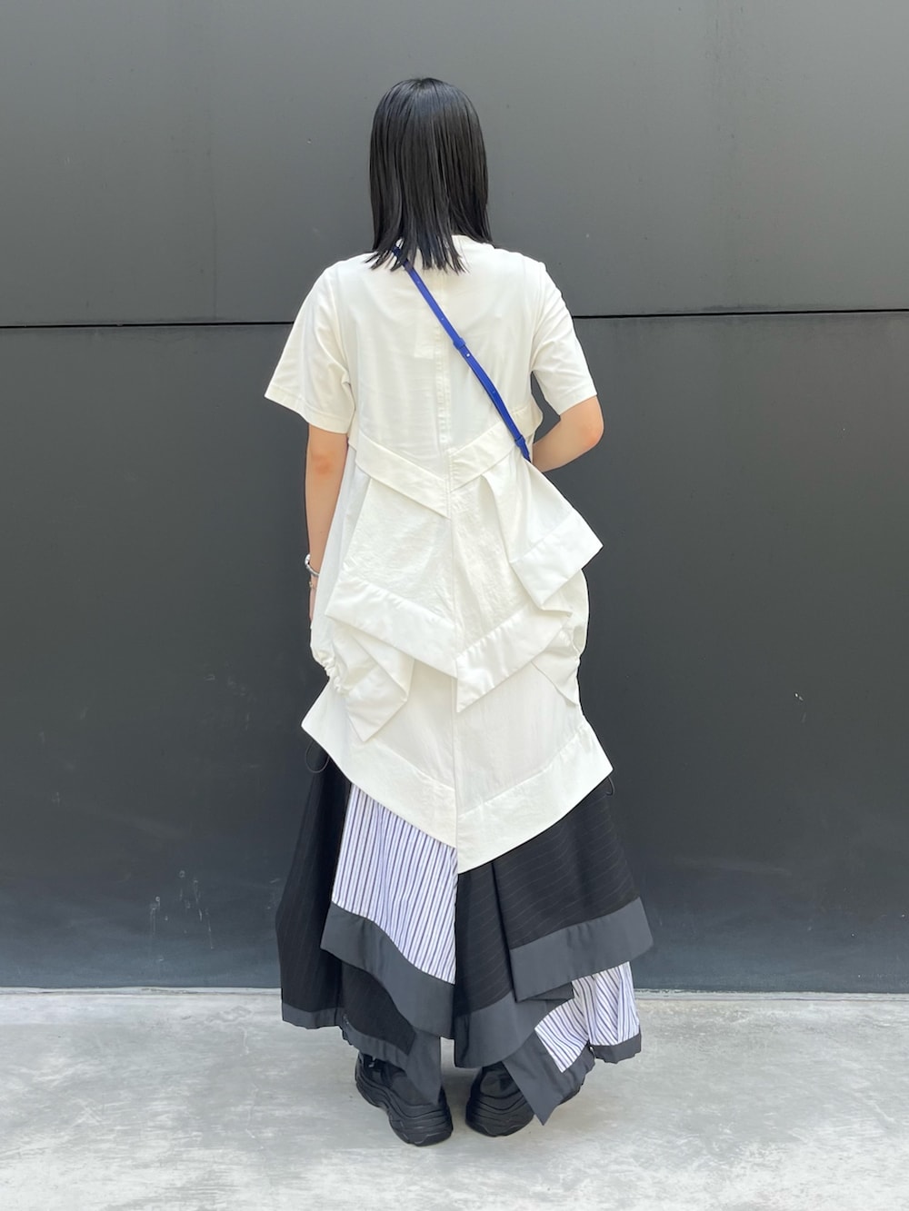 その他のスカート、ブルー系のショルダーバッグ、ブラック系のスニーカーを着用したレディースの夏コーディネートの4枚目の写真
