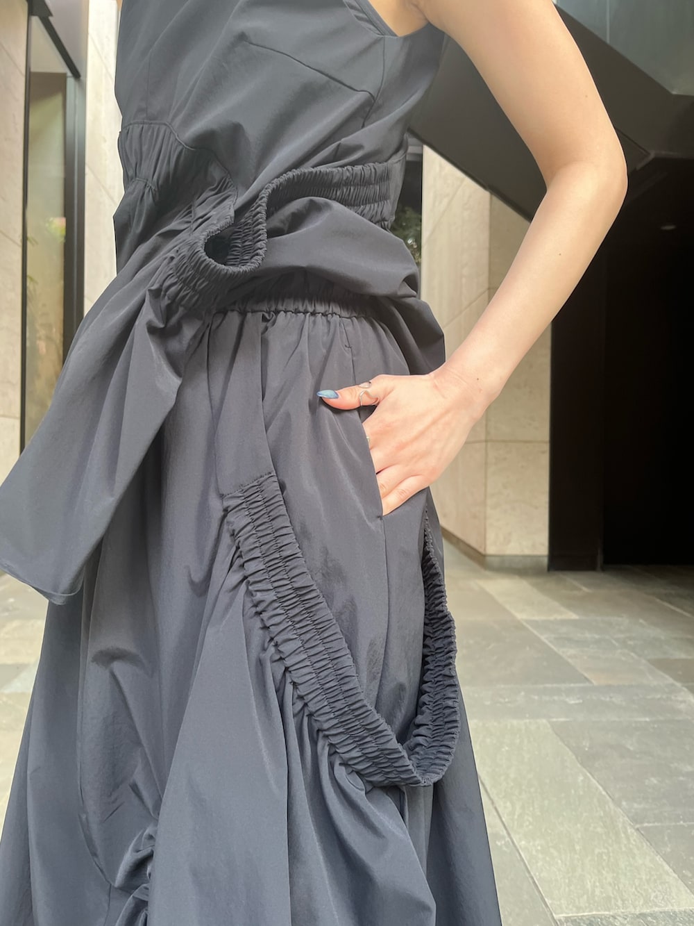 ブラック系のタンクトップ、ブラック系のスカート、ブラック系のサンダルを着用したレディースの春コーディネートの9枚目の写真