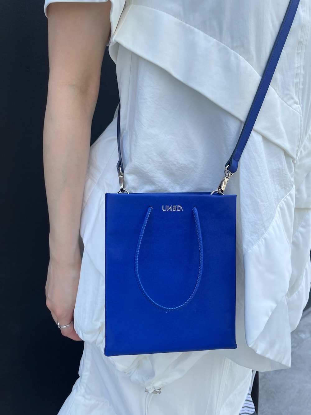 その他のスカート、ブルー系のショルダーバッグ、ブラック系のスニーカーを着用したレディースの夏コーディネートの10枚目の写真