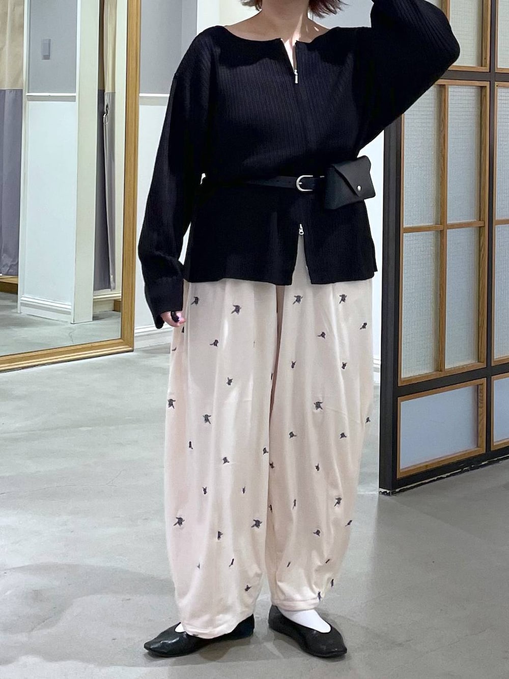 ホワイト系のその他パンツ、ブラック系のカーディガン/ボレロ、ブラック系のベルトを着用したレディースの秋コーディネートの2枚目の写真