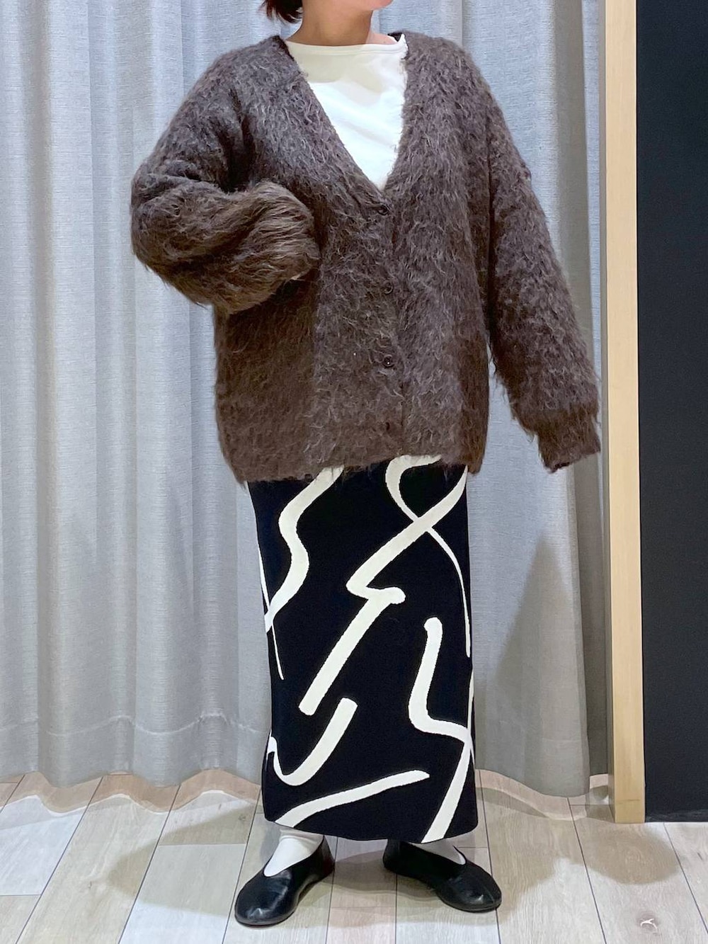 ホワイト系のその他トップス、ブラック系のスカート、ブラウン系のカーディガン/ボレロを着用したレディースの秋コーディネートの2枚目の写真