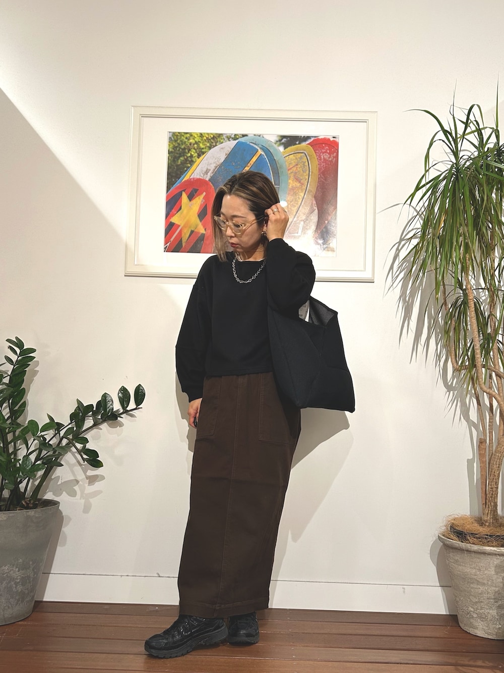 ブラック系のTシャツ/カットソー、ブラウン系のスカート、ブラック系のスニーカーを着用したレディースの冬コーディネートの2枚目の写真