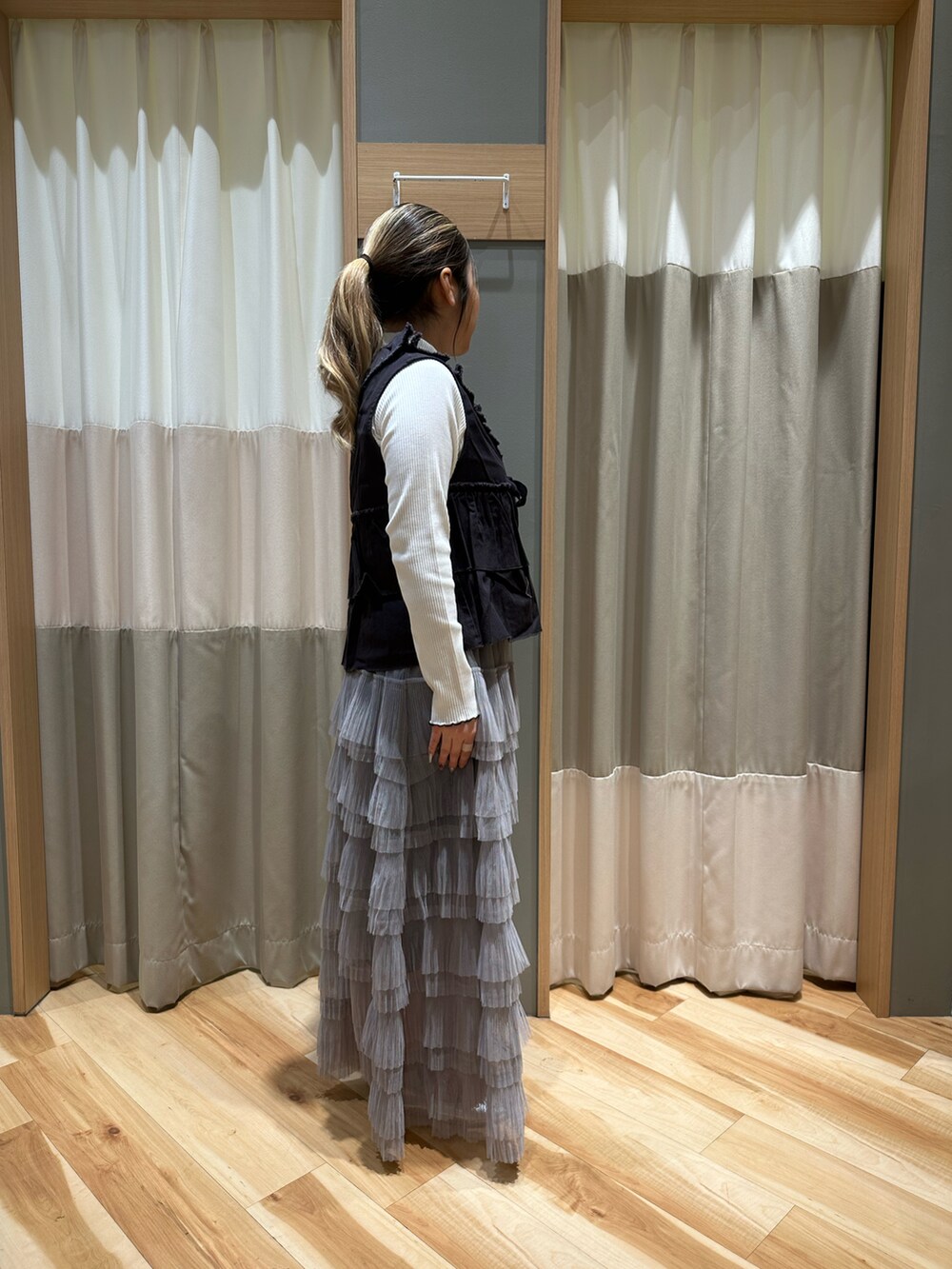 ブラック系のベスト、ホワイト系のTシャツ/カットソー、グレー系のスカートを着用したレディースの冬コーディネートの4枚目の写真