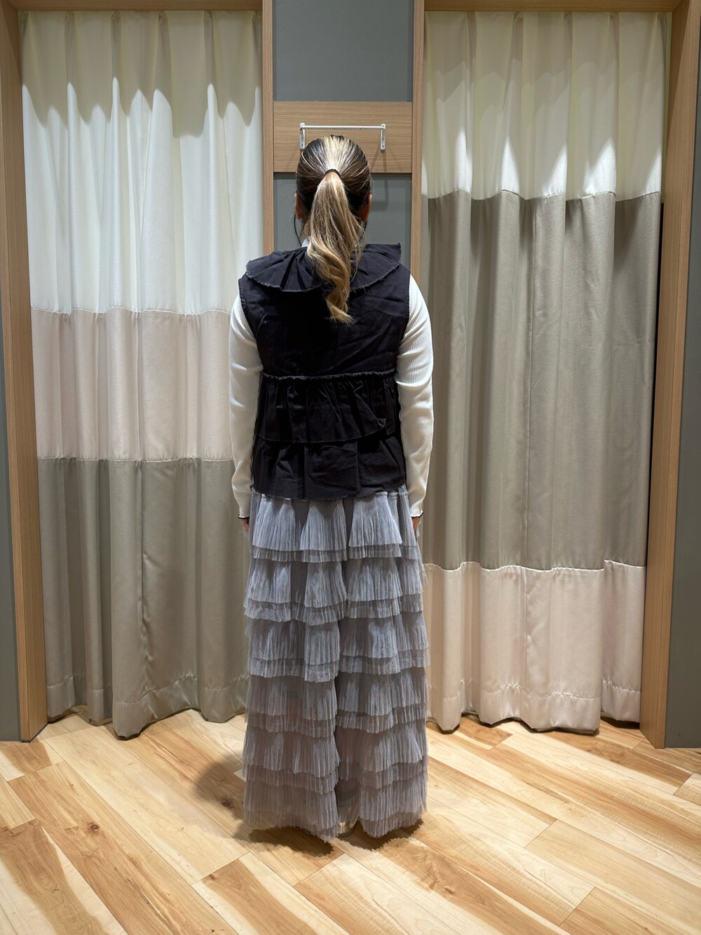 ブラック系のベスト、ホワイト系のTシャツ/カットソー、グレー系のスカートを着用したレディースの冬コーディネートの3枚目の写真