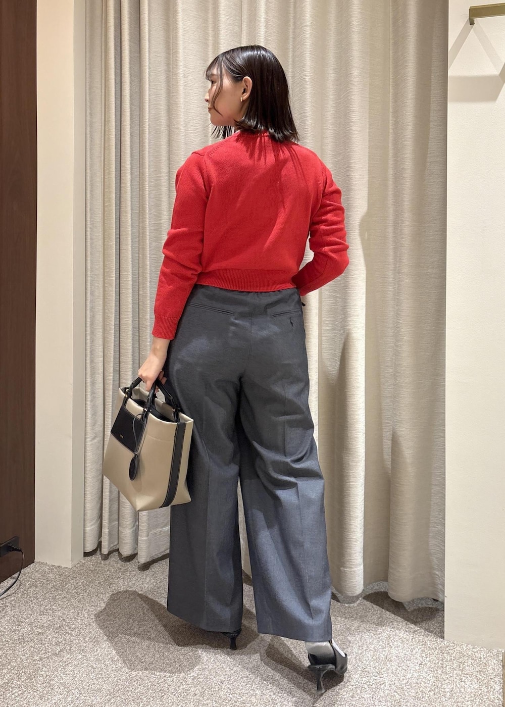 ベージュ系のトートバッグ、ブルー系のスラックス、レッド系のカーディガン/ボレロを着用したレディースの冬コーディネートの4枚目の写真