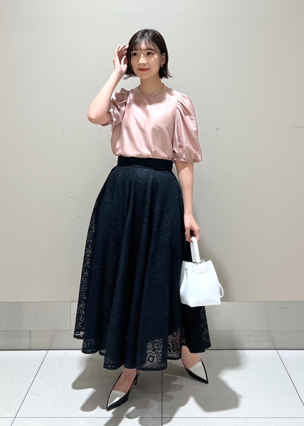 ホワイト系のハンドバッグ、ブラック系のパンプス、ピンク系のシャツ/ブラウスを着用したレディースの春コーディネートの2枚目の写真