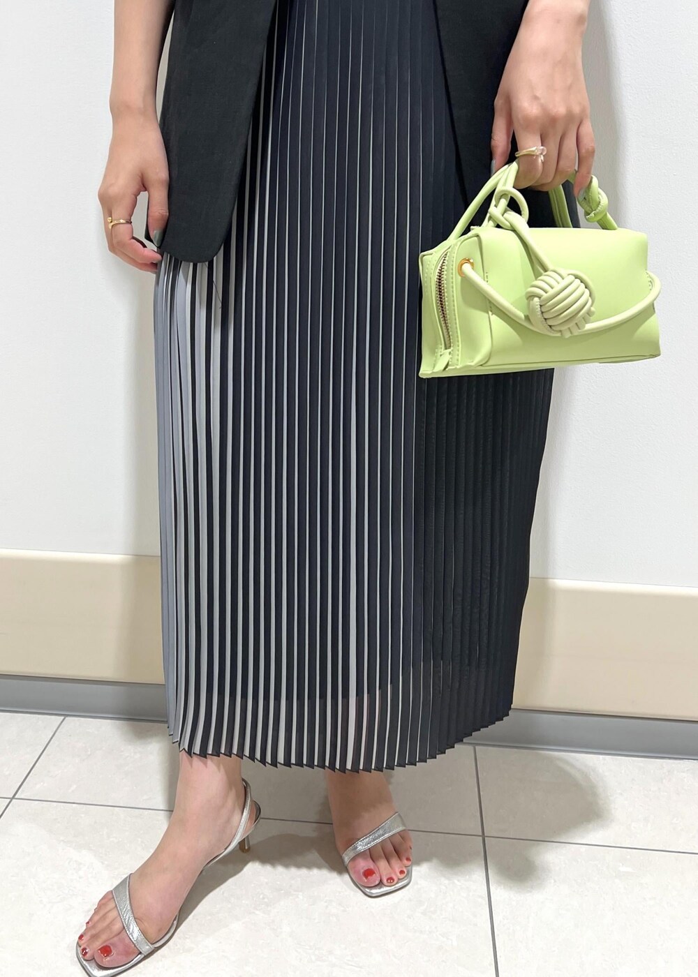 シルバー系のサンダル、グリーン系のショルダーバッグ、ブラック系のスカートを着用したレディースの夏コーディネートの10枚目の写真