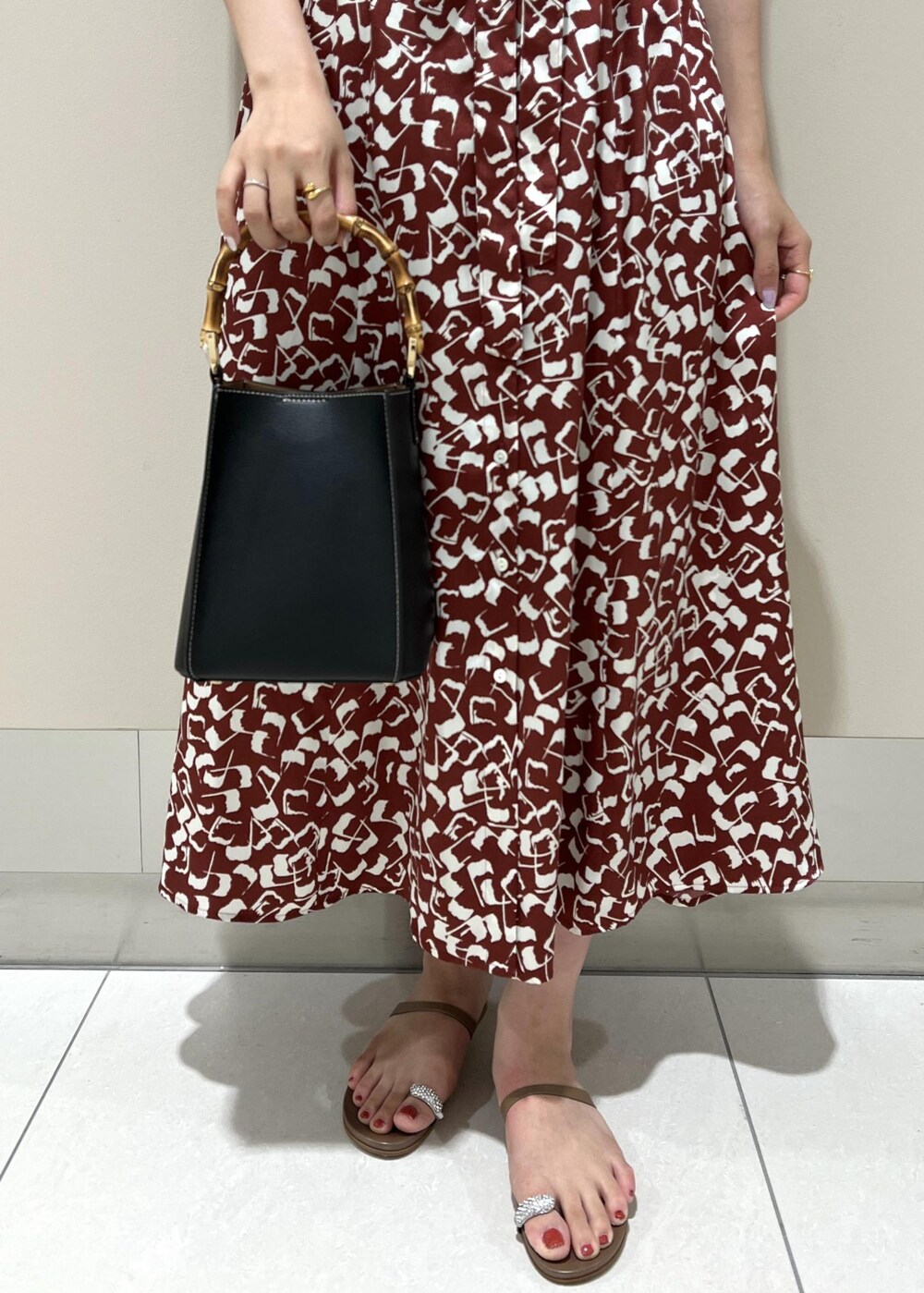 ブラック系のハンドバッグ、ベージュ系のサンダル、レッド系のワンピースを着用したレディースの夏コーディネートの7枚目の写真