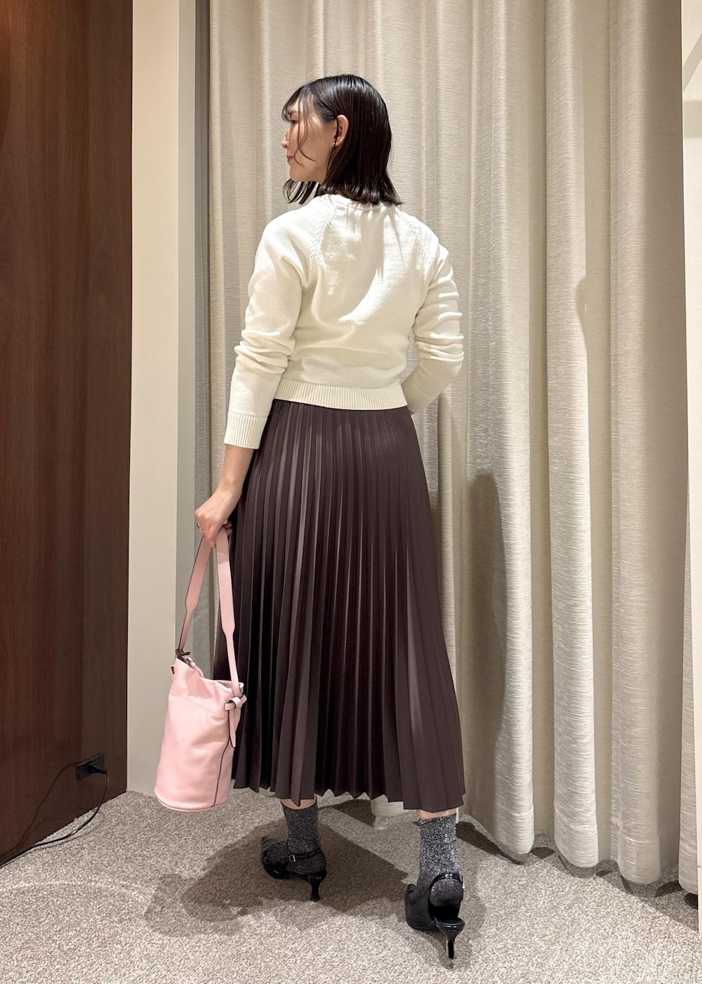 ピンク系のハンドバッグ、ブラウン系のスカート、ホワイト系のニット/セーターを着用したレディースの春コーディネートの4枚目の写真