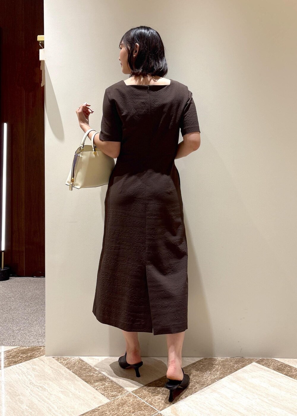 ホワイト系のハンドバッグ、ブラック系のサンダル、ブラウン系のワンピースを着用したレディースの夏コーディネートの4枚目の写真