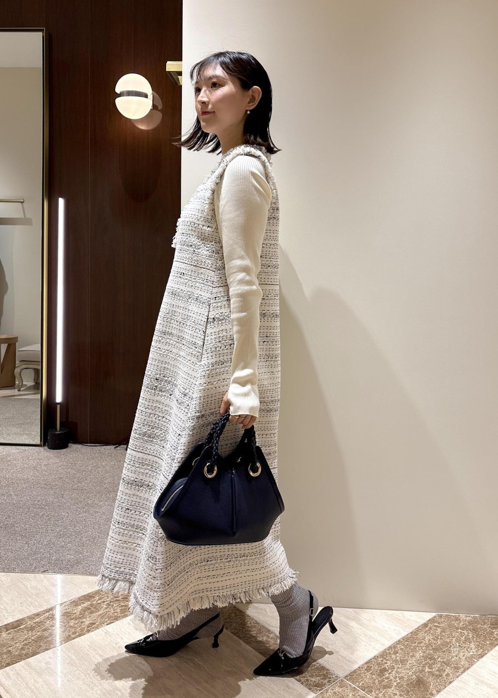 ブラック系のパンプス、ホワイト系のワンピース、ホワイト系のニット/セーターを着用したレディースの春コーディネートの3枚目の写真