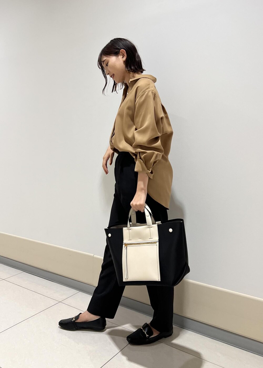 ブラック系のハンドバッグ、ベージュ系のシャツ/ブラウス、ブラック系のその他パンツを着用したレディースの秋コーディネートの2枚目の写真