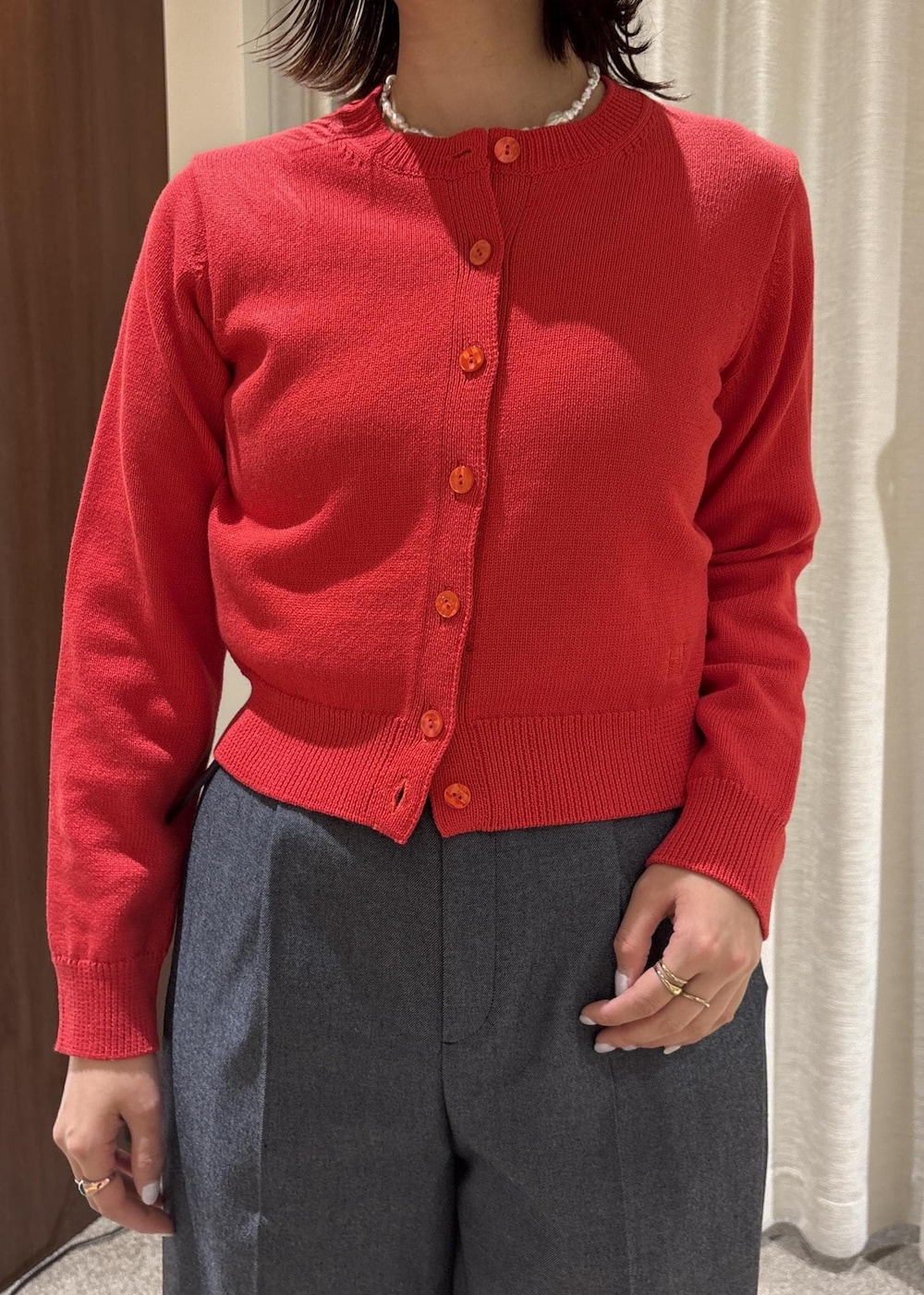 ベージュ系のトートバッグ、ブルー系のスラックス、レッド系のカーディガン/ボレロを着用したレディースの冬コーディネートの5枚目の写真