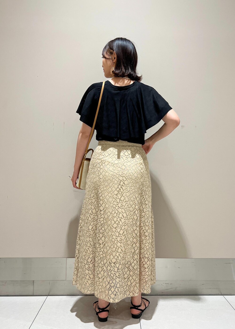 ベージュ系のハンドバッグ、ブラック系のニット/セーター、ベージュ系のスカートを着用したレディースの春コーディネートの3枚目の写真