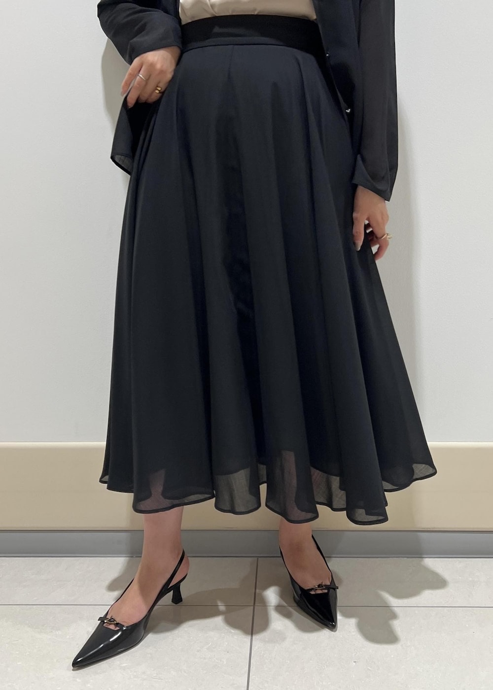 レッド系のハンドバッグ、ベージュ系のキャミソール、ブラック系のパンプスを着用したレディースの秋コーディネートの7枚目の写真